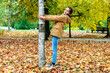 © Ludmila - A cute happy girl stands by a birch tree in a city autumn park.