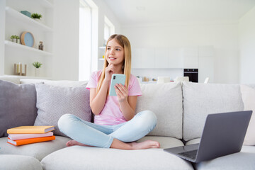 Wall Mural - Full size photo of minded smart kid girl sit comfort couch legs crossed rest relax use smartphone think thoughts decide what post in house indoors homeschool