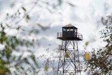 An Old Abandoned Observation Military Tower, Hidden Behind Bushes And Trees