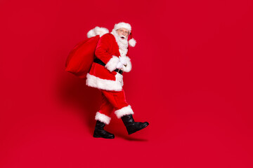 Wall Mural - You caught me. Photo portrait of scared impressed santa claus with open mouth carrying big bag of presents isolated on vivid red colored background