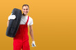 © Angelov - car mechanic carrying tire on yellow background. happy man smiling amd looking into camera