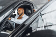 © fotofabrika - Young attractive woman salesperson in car showroom showing a car to her male client