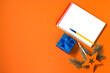 © TATIANA - New Year concept. Notepad and pen to write down goals or plans for the coming year. Christmas toys, blue gift box on an orange background. Flat lay, top view, lifestyle. Copy space