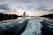 © fesenko - view on active athletic woman jumping over splashing wave on surf style wakeboard.