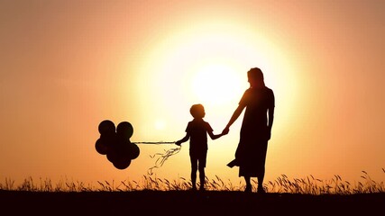 silhouette of a happy family at sunset. a mother and a child with balloons hold each other's hands. 