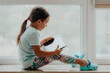 European Little Girl with Tablet pc Relaxing in a spacious room near the Window. 