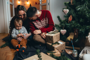 family decorating christmas tree and packing gifts at home