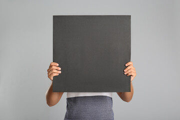 Sticker - Man holding black blank poster on grey background. Mockup for design