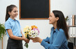 © New Africa - Schoolgirl congratulating her pedagogue with bouquet in classroom. Teacher's day