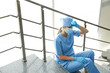© New Africa - Exhausted doctor sitting on stairs in hospital. Stress of health care workers during COVID-19 pandemic