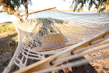 Hat in comfortable hammock on beach, closeup. Summer vacation