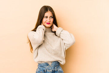 Young caucasian woman isolated en beige background suffering neck pain due to sedentary lifestyle.