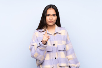 Wall Mural - Young Indian woman isolated on blue background frustrated and pointing to the front