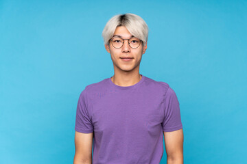 Wall Mural - Young asian man over isolated blue background with glasses and happy