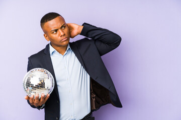 Wall Mural - Young latin man holding a ball party isolated touching back of head, thinking and making a choice.