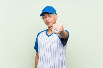 Wall Mural - Young asian man playing baseball over isolated green background