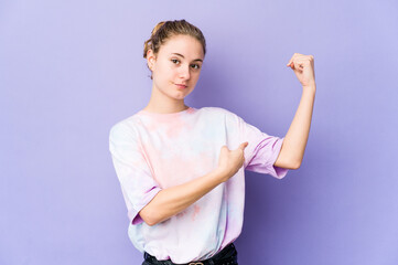 Wall Mural - Young caucasian woman on purple background showing strength gesture with arms, symbol of feminine power