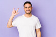 Young caucasian man isolated on purple background showing a horns gesture as a revolution concept.