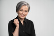 © Svyatoslav Lypynskyy - Charming gray haired woman wearing black shirt smiles at camera, isolated on white background. Mature Caucasian woman in studio raised her elbow bending arm. High quality photo.