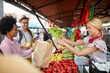 © luckybusiness - Seller woman offers fresh and organic vegetables at the green market or farmers market stall.  Young buyers choose and buy products for healthy food in grocery. All for diet healthy eating, lifestyle.