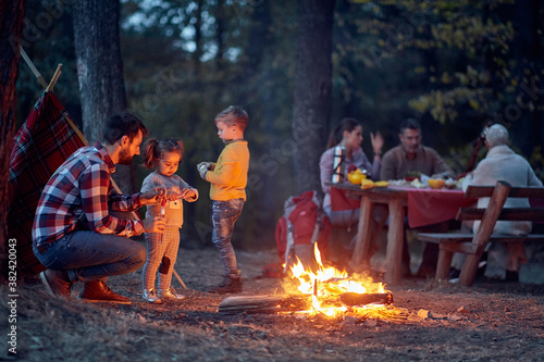 Family camping in the woods; Spring or autumn camping with campfire at night ; camping, travel, tourism, hike and people concept. Quality family time together.