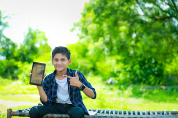 technology and people concept - smiling teenage boy in blue shirt showing smartphone with blank screen