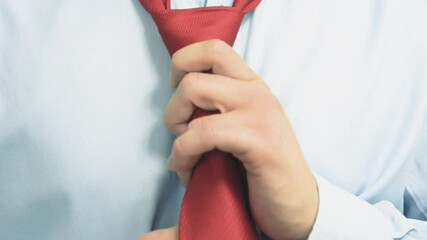 Poster - The man is putting on his tie. The concept of getting ready for work, for an important celebration. A man wearing a shirt ties and puts on a red tie.