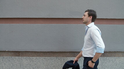 Closeup man walking near building. Businessman carrying suit jacket at street