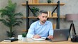 © viacheslav - Focused gray-haired business man listens employee remote online video call conference web cam meeting chat. Bearded man in home office wears wireless earphones uses laptop computer