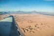Airplane wing on the background of the Sahara. Endless yellow sandy hot desert.