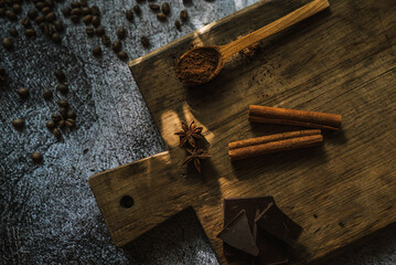 Wall Mural - coffee, dark chocolate, cinnamon sticks and spices on a brown wooden board