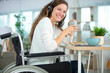 © auremar - young woman in wheelchair eating breakfast and wearing headphones