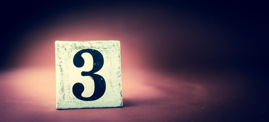 Old vintage wooden block with digit 3, number three - vivid maroon background