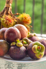 Wall Mural - set fruit asia tropical fresh mangosteen and passion fruit lies on a plate on a background of rambutan branch