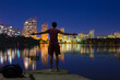 © Hennadii - A guy stands on the banks of the Dnieper river against the background of a bright night embankment