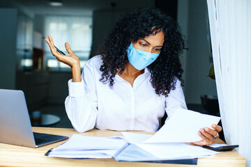 Wall Mural - Portrait of a person sitting at desk wearing face mask, reading paper bill shocked, surprised or upset