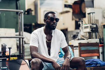 Wall Mural - Portrait photo young stylish black man in a white T-shirt and glasses in old factory. Street photo. african american people.