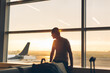 © Mosuno/Stocksy - Man Sitting at the Airport Gate and Enjoying Sunrise