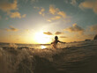 © FrameWorks/Stocksy - Woman jumping into waves in sea at sunset