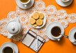 © Audrey Shtecinjo/Stocksy - Coffee cups with cookies on tablecloth on orange background / ook from above