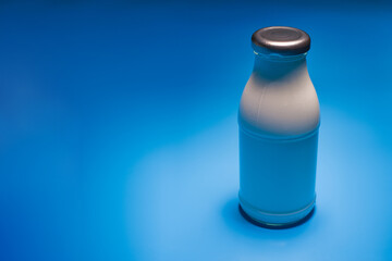 Bottle of milk on blue background with copy space.