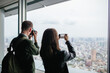 © BONNINSTUDIO/Stocksy - Tourist friends taking photos of Tokyo skyscraper.