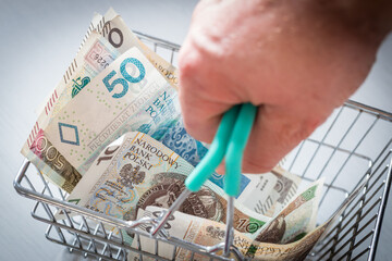 Shopping basket filled with money from Poland. The concept of rising prices in stores and rising inflation