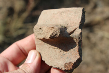 Human hand holding a pottery sherd