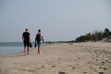 Two men walking along the beach by the sea on a sunny day