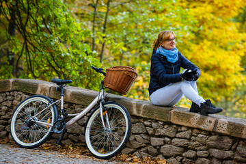 Wall Mural - Woman resting, sitting in park next to her bicycle