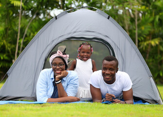 Wall Mural - Happy African American family spending time together during vacation on the camping tent outdoor national park