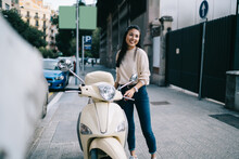 Funny Female Tourist Dressed In Casual Clothing Rejoicing At Urban Street Ready For Driving Getaway Adventure On Retro Moped Bike, Toothy Asian Hipster Girl Laughing Near Vintage Rented Motorcycle