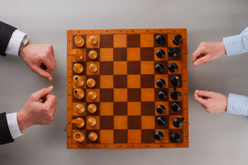 Wall Mural - Top view of male and female hands with chess board. Business people playing chess. People, business, competition and leadership concept.