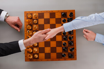 Wall Mural - Business people shaking hands over chess board. Handshake of business people after playing chess game.